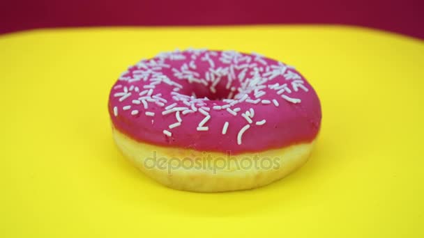 Läckra söta donut roterar på en tallrik. Ovanifrån. Ljusa och färgglada beströdda donut närbild makro skott spinning på gul bakgrund. — Stockvideo
