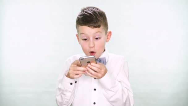 Niño jugando con una tableta o teléfono inteligente sobre fondo blanco — Vídeo de stock