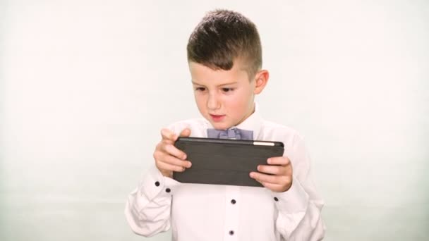 Junge spielt mit Tablet oder Smartphone auf weißem Hintergrund — Stockvideo