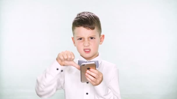 Junge zeigt Daumen nach unten und spielt mit Tablet oder Smartphone auf weißem Hintergrund — Stockvideo