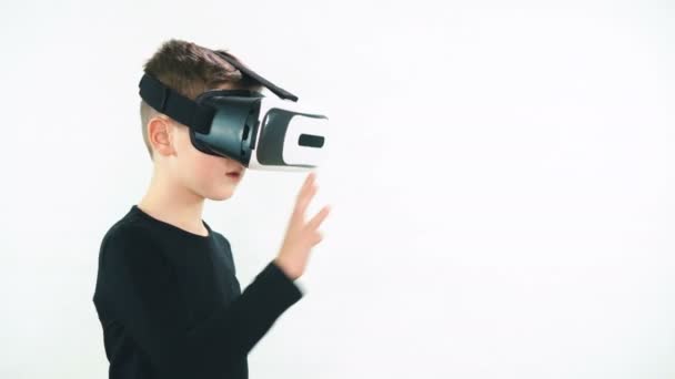 Niño en realidad virtual auriculares de pie en la habitación blanca y mirando a su alrededor en asombro, diez tratando de tocar algo invisible — Vídeos de Stock