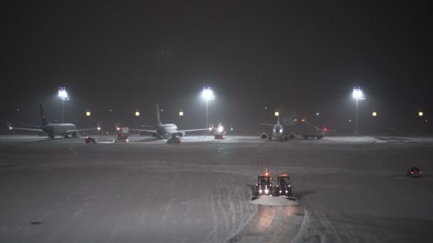 Una tormenta de nieve en el aeropuerto. Trabajadores y coches de servicio trabajan cerca de aviones — Vídeos de Stock