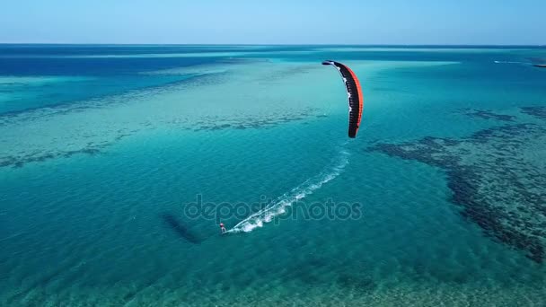 Vista aérea joven hombre kite surf en tropical azul océano — Vídeo de stock