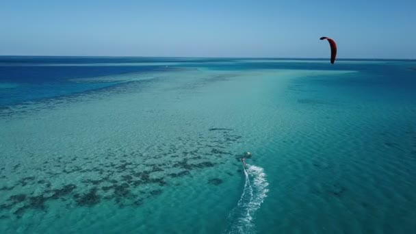 Vista aérea joven hombre kite surf en tropical azul océano — Vídeo de stock