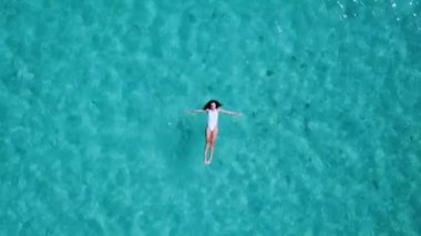 Havadan görünümü. Güzel genç kadın beyaz bikini berrak Turkuaz rengi okyanus su yüzeyinde yüzen