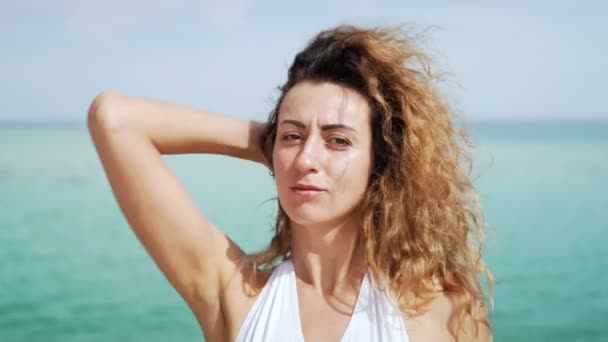 Gyönyörű, fiatal nő portréja közelről. fúj a szél a trópusi tengerparton lassítva. — Stock videók