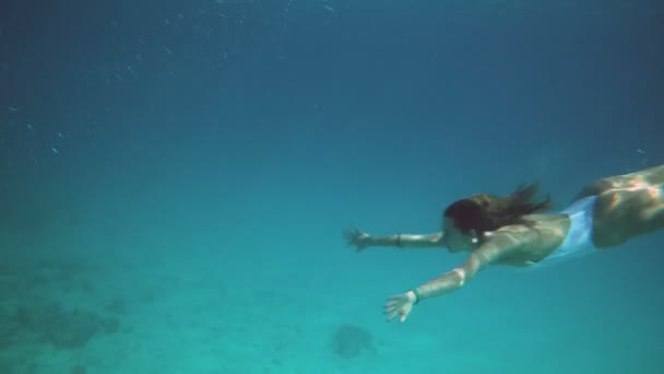 Frau in blauem Badeanzug schwimmt in Zeitlupe unter Wasser — Stockvideo