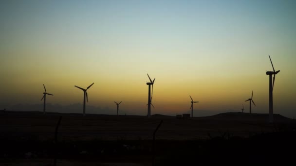 4k wunderschöne Windkraftanlagen, die saubere, grüne Windenergie nutzbar machen, die mit Sonnenstrahlen in den Sonnenuntergangshimmel gehüllt ist. grüne Energie. — Stockvideo