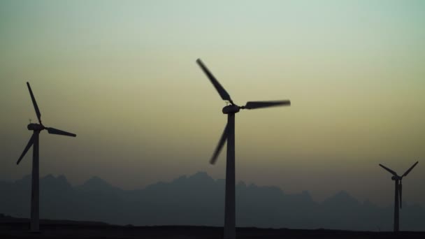 4K Hermosas turbinas de molino de viento aprovechando limpio, verde, la energía eólica silueta en el cielo puesta del sol con los rayos del sol. Energía verde . — Vídeos de Stock
