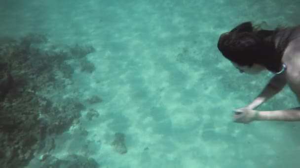 Frau in blauem Badeanzug schwimmt in Zeitlupe unter Wasser — Stockvideo