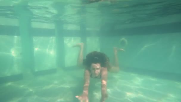 Женщина в синем купальнике плавает под водой в замедленной съемке — стоковое видео