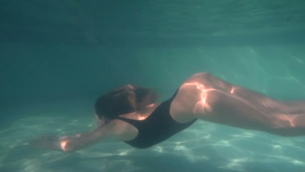 Mujer en traje de baño azul nadando bajo el agua en cámara lenta — Vídeo de stock