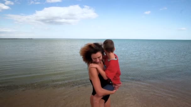 El niño y la mamá en una playa se juegan, abrazan y besan. En cámara lenta. 120 fps — Vídeo de stock