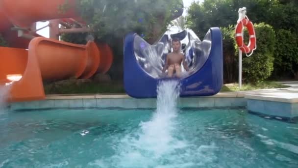 Мальчик плюхается в бассейн, замедленная съемка — стоковое видео