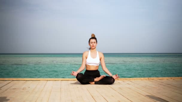 La ragazza sta facendo yoga posa sulla spiaggia dell'isola. Statica. Mare o oceano felice donna relax. Acqua e nuvole. Mani e cielo blu . — Video Stock