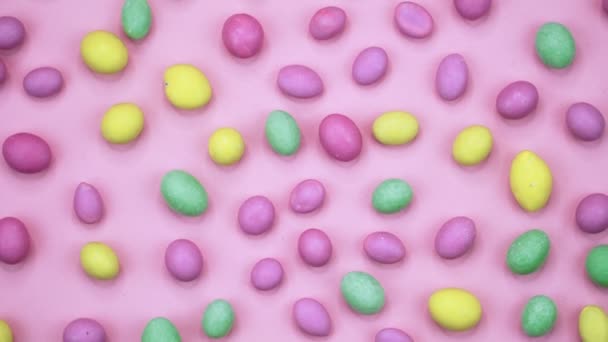 Macro video van smakelijke krokante ronde snoepjes geïsoleerd op roze achtergrond. Geel, oranje, groen, roze en blauwe snoepjes draaien. Realtime 4k — Stockvideo