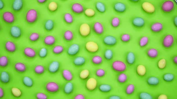 Macro video van smakelijke krokante ronde snoepjes geïsoleerd op groene achtergrond. Geel, oranje, groen, roze en blauwe snoepjes draaien. Realtime 4k — Stockvideo