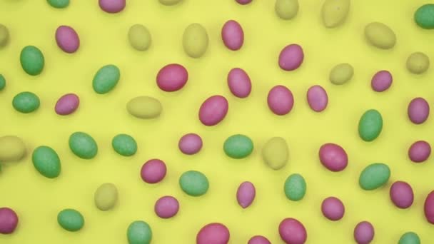 Macro video of tasty crispy round candies isolated on yellow background. Yellow, orange, green, pink and blue sweets rotating. Real time 4K — Stock Video