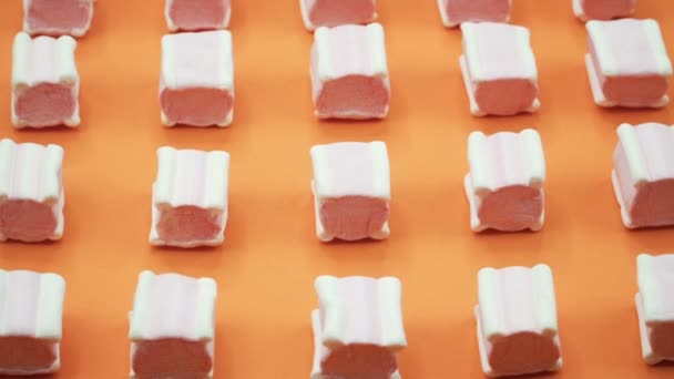 Světlé a barevné marshmallows makrofotografie střílel na oranžové pozadí. Rotující pohled shora. — Stock video