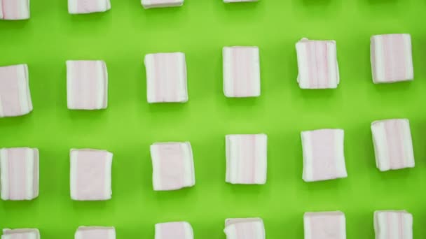 Ljusa och färgglada marshmallows närbild makro skott på en grön bakgrund. Roterande ovanifrån. — Stockvideo