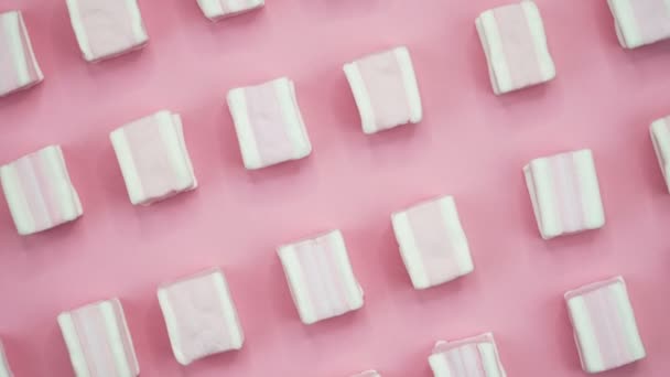 Helle und farbenfrohe Marshmallows in Nahaufnahme auf rosa Hintergrund. Drehende Ansicht von oben. — Stockvideo