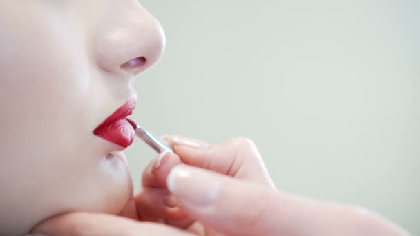 Close-up de uma menina de beleza atraente fazendo maquiagem completa. Mulher aplicando lábio vermelho — Vídeo de Stock