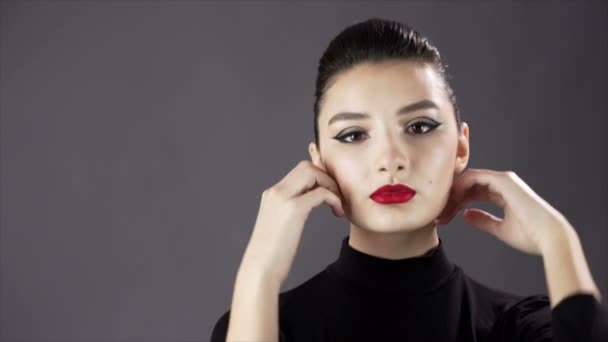 Portret van een mooie sexy meisje. Fotomodel poseren op een donkere achtergrond voor studio fotoshoot. Langzame mo. close-up. Rode lippen — Stockvideo