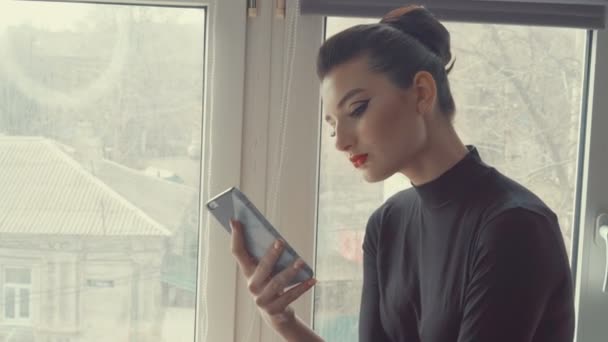 Gadis cantik dengan smartphone. Wanita bisnis muda menggunakan ponsel layar sentuh di latar belakang kota jendela. Orang, teknologi, koneksi . — Stok Video