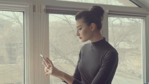 A csinos lány a smartphone. Fiatal üzleti nő segítségével érintőképernyős telefon ablak város háttérben. Az emberek, a technológia, a kapcsolat. — Stock videók