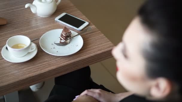 Frau im Café trinkt Kaffee mit Kuchen und checkt Smartphone — Stockvideo