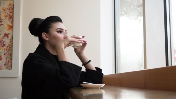 Молода, красива жінка п'є каву — стокове відео