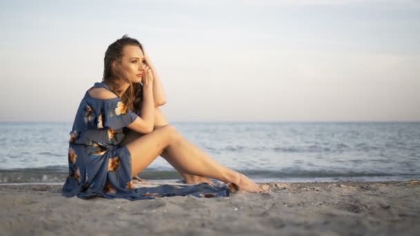 Joven chica alegre atractiva sentada en la playa — Vídeo de stock