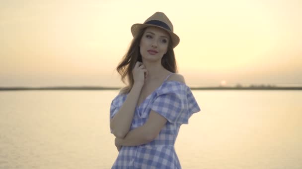 Vonzó nő kalapot és ruhát ült, és nézte a naplementét — Stock videók