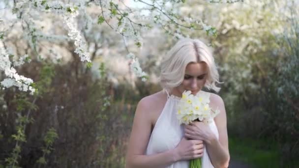 Ragazza bionda che cammina su un giardino fiorito e riposa — Video Stock