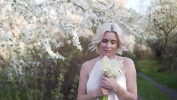 Blond dívka chůze na rozkvetlé zahrady a odpočinek — Stock video