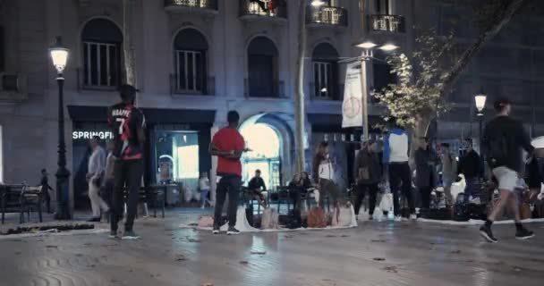 Barcellona, Spagna - 20 ottobre 2019: Migranti neri, venditori ambulanti per le strade di Barcellona di notte. Il problema dell'immigrazione clandestina in Europa. Timelapse . — Video Stock