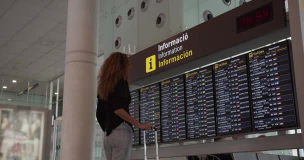 Barcelona, Espanha - 20 de outubro de 2019: passageira mulher olhando para tela de tabela de horários no aeroporto, voo internacional . — Vídeo de Stock