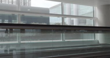 Valizli kadın yürüyen merdivende duruyor ve havaalanındaki akıllı telefonun başında konuşuyor..