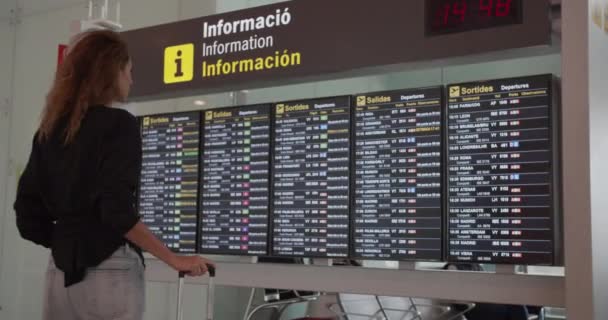 Barcelona, Espanha - 20 de outubro de 2019: passageira mulher olhando para tela de tabela de horários no aeroporto, voo internacional . — Vídeo de Stock