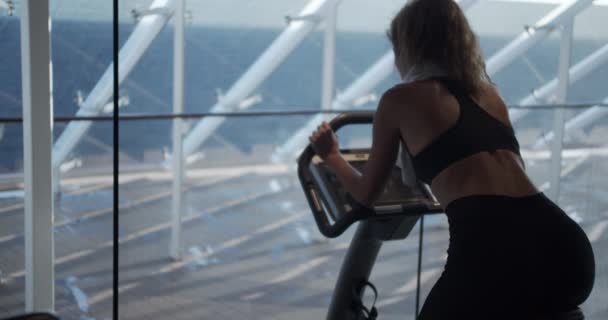 La mujer en el gimnasio en una bicicleta estática . — Vídeo de stock