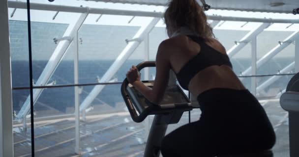 De vrouw in de sportschool op een hometrainer. — Stockvideo