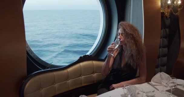 Estilo de vida luxuoso - Mulher bebendo champanhe. Senhora elegante segurando copo de vinho e olhando na janela sobre o oceano desfrutando de uma vista incrível sobre férias de luxo .. — Vídeo de Stock