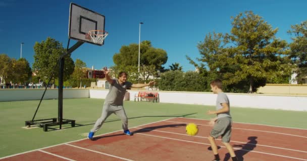 Vader met zoon basketbal spelend op het buitenveld. — Stockvideo