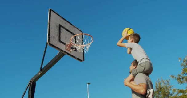 Far och son njuta av en spela basket. — Stockvideo