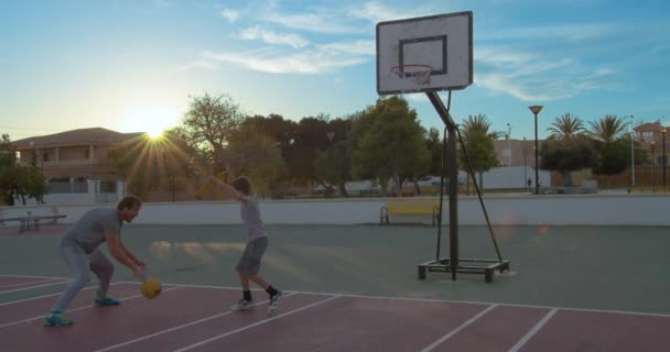 Padre e figlio che intrecciano la pallacanestro nel cerchio con il bagliore solare . — Video Stock