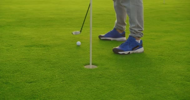 Golfista bater bola de golfe para baixo no buraco no belo campo de golfe no pôr-do-sol brilhante.Golf conceito de esporte. Fechar. . — Vídeo de Stock
