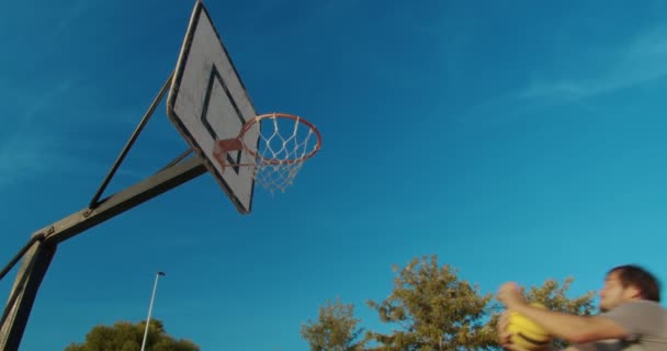 Homme joueur de basket slam plongeant sur un terrain de basket en plein air . — Video