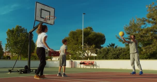 Familia jugando baloncesto en el campo de deportes . — Vídeos de Stock