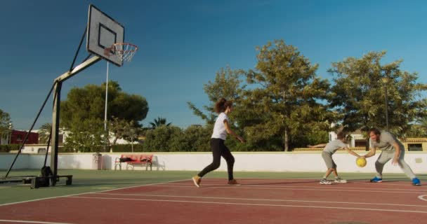 Familjen spelar basket på idrottsplatsen. — Stockvideo