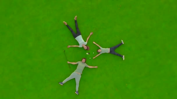 Aerial view. Family lies on a golf course resting after plaing golf. Concept of family relaxing together and sport. — Stok video